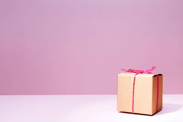 Caja de regalo artesanal de cartón sobre fondo rosa macizo. Vacaciones a — Foto de Stock