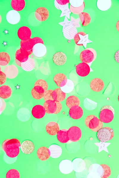 Confettis multicolores rose, or et blanc sur fond vert menthe audacieux, fond de fête — Photo