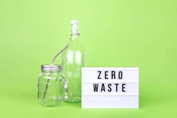 Herbruikbare glazen fles en pot met metalen rietje en bioscoop lichtbak op de lichtgroene druppel — Stockfoto