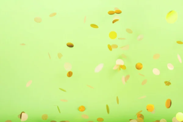 Złote konfetti padające na odważne neonowe zielone tło, świąteczne tło — Zdjęcie stockowe