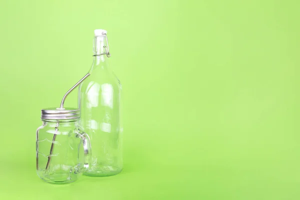 Herbruikbare glazen fles en pot met metalen rietje op de lichtgroene druppel — Stockfoto