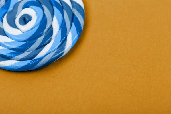 Big blue lollipop on solid dark yellow background