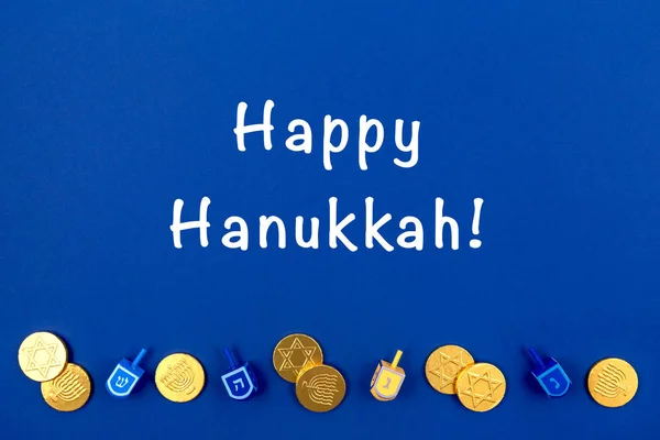 Fundo azul escuro com dreidels multicoloridos e moedas de chocolate e Happy Hanukkah. Hanukkah e conceito feriado judaico . — Fotografia de Stock