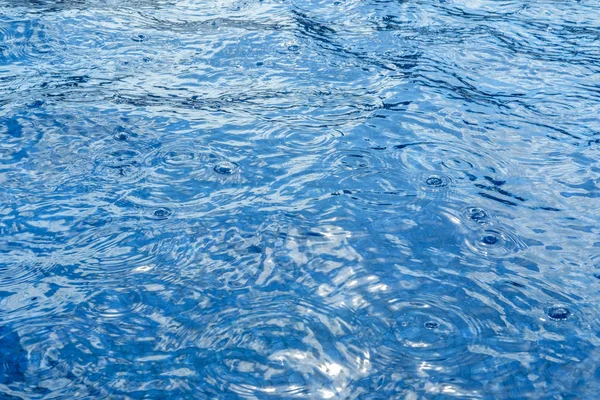 Blauw water oppervlak textuur tijdens regen. Monochrome klassieke blauwe achtergrond met plaats voor tekst — Stockfoto