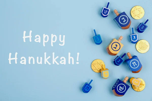 Fundo azul com dreidels multicoloridos e moedas de chocolate e Happy Hanukkah redação. Hanukkah e conceito feriado judaico . — Fotografia de Stock