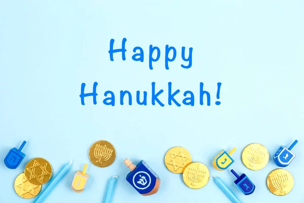 Fondo azul con dreidels multicolores, velas menora y monedas de chocolate y la redacción feliz Hanukkah. Hanukkah y judaic concepto de vacaciones . — Foto de Stock