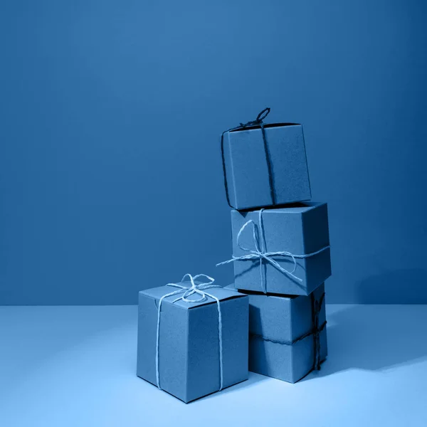 Cajas de regalo de cartón artesanal sobre el sólido fondo azul clásico. Concepto de vacaciones y regalo — Foto de Stock