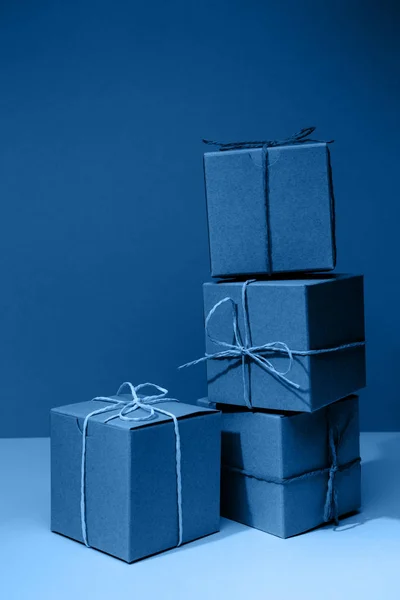 Cajas de regalo de cartón artesanal sobre el sólido fondo azul clásico. Concepto de vacaciones y regalo — Foto de Stock