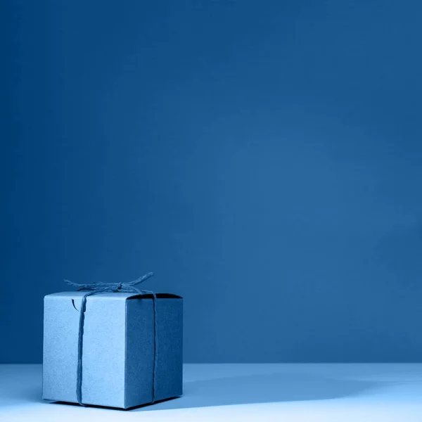 Caja de regalo de cartón artesanal sobre el sólido fondo azul clásico. Concepto de vacaciones y regalo — Foto de Stock
