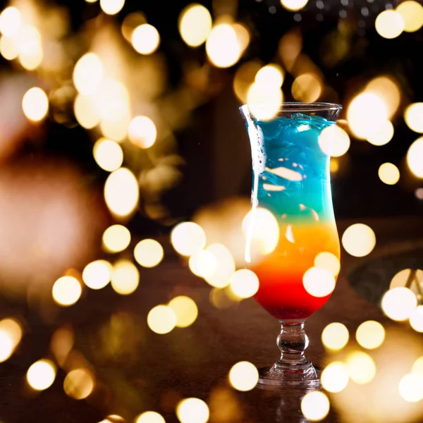 Rainbow cocktail with festive bokeh lights — Stock Photo, Image