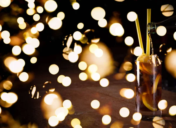 Barman prepara Cuba libre cocktail in un bicchiere alto con luci festive bokeh — Foto Stock