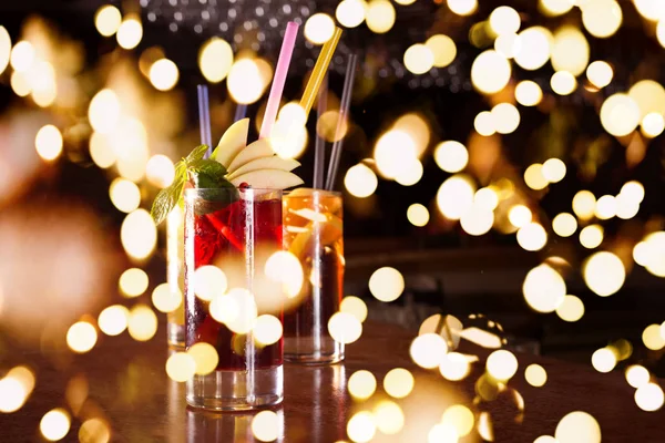 Bomba de cereza, destornillador y cócteles cuba libre en vasos altos con luces festivas bokeh —  Fotos de Stock