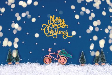 Noel oyuncaklarıyla süslü komik bir sahne klasik mavi ve Bokeh ışıkları. Noel ağacı eve kar yolunda bisikletle taşınır.