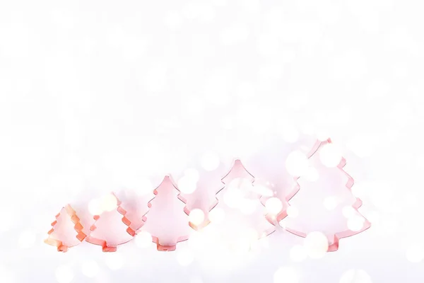 Flatlay with row of holiday tree copper cutters on white sparkling background. Концепция праздника, Рождества и Нового года. Уютные домашние детали с праздничными огнями боке — стоковое фото