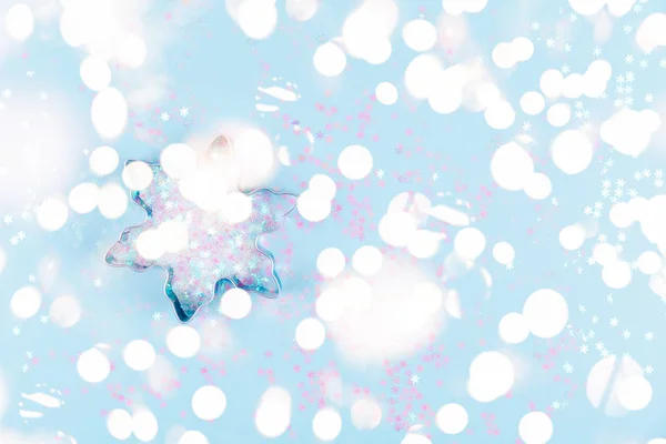 Flatlay mit Schneeflocke Ausstecher und Schneeflocke Streusel auf blauem Hintergrund. Urlaub, Weihnachten und Neujahr Konzept. heimelige Details mit festlichem Bokeh-Licht — Stockfoto