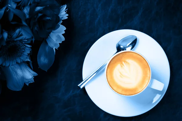 Taza de café con arte latte y ramo de flores. Concepto de evento de negocios refrescante descanso en tono azul clásico — Foto de Stock