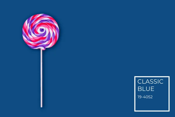 Big lollipop on solid classic blue background with color name tag — Stock Photo, Image