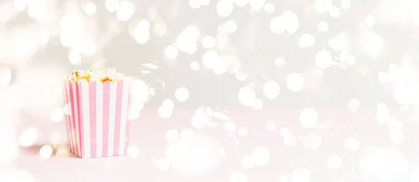 Torba z popcornem w białe i różowe paski na świątecznym tle światła bokeh. Puste minimalistyczne tło. Romantyczny wieczór filmowy i koncepcja przekąsek — Zdjęcie stockowe