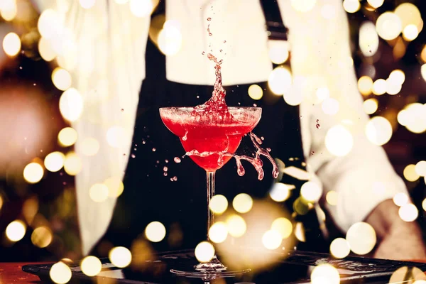 Barman in making cocktail at a nightclub. Nightlife concept. No face. Pouring into glass with festive bokeh lights — Stock Photo, Image