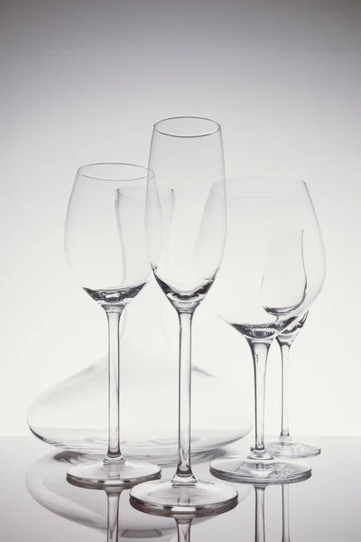 Seleção de copos com vinho, champanhe, copos de licor e decantador no fundo claro em tonificação a frio claro — Fotografia de Stock