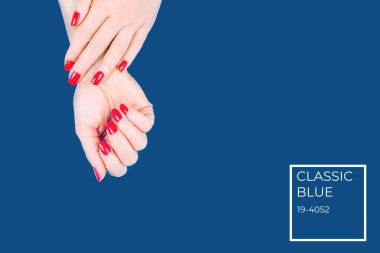 Mavi arka planda kırmızı manikürlü kadın elleri. Renkli isim etiketli tatil, parti ve güzellik konsepti