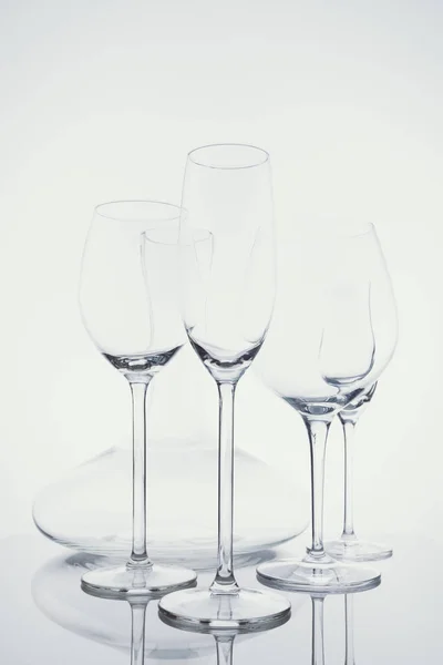 Вибір скляного посуду з вином, шампанським, келихами для напоїв та декантером на світлому фоні в легкому холодному тонуванні — стокове фото