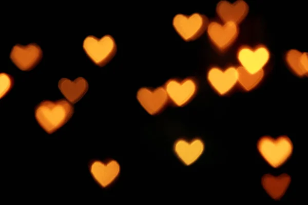 明るい暖かい心の形をしたボケのライトと黒の背景。休日、バレンタインデーの背景。どんなデザインでもレイヤーに最適 — ストック写真