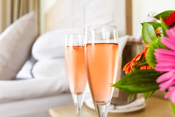 Dos copas de champán rosa en la lujosa habitación del hotel. Citas, romance, luna de miel, San Valentín, escapada, estancia, conceptos de desintoxicación digital — Foto de Stock