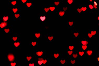 Siyah arka plan, parlak kırmızı sıcak kalp şeklinde bokeh ışıkları. Tatil, Sevgililer Günü geçmişi. Herhangi bir tasarım için ideal