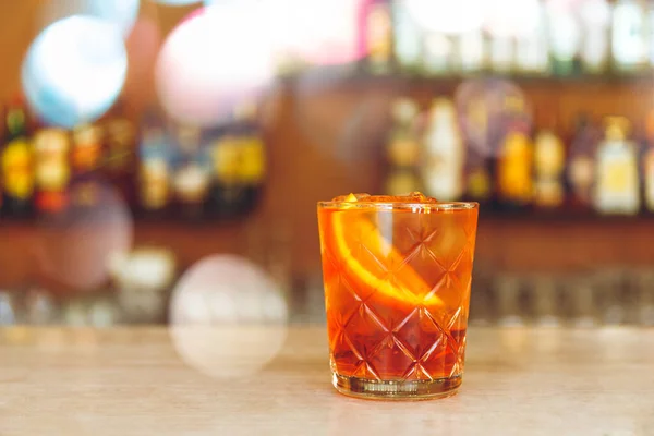Et glass velsmakende, alkoholholdig negroni-cocktail med appelsinskive står på bardisken. . – stockfoto