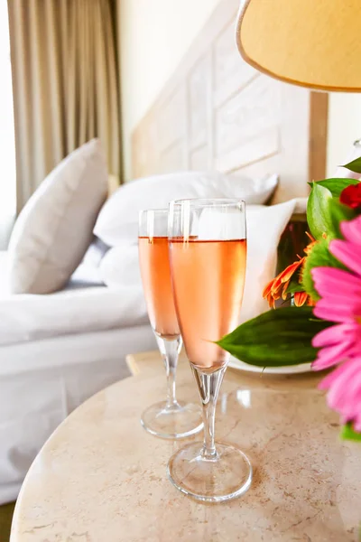 Two glasses of rose champagne in the upscale hotel room. Dating, romance, honeymoon, valentine, getaway, staycation, digital detox concepts — Stock Photo, Image