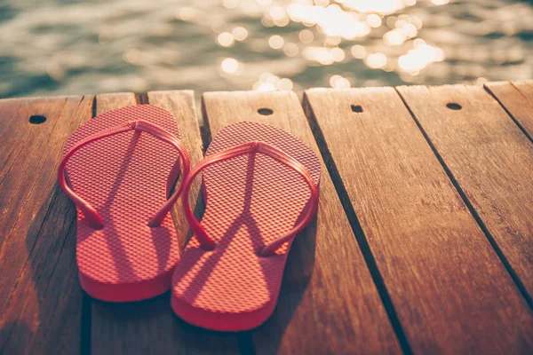 Chanclas en el muelle de madera al atardecer. Resort de vacaciones de lujo. Concepto de escapada de vacaciones — Foto de Stock