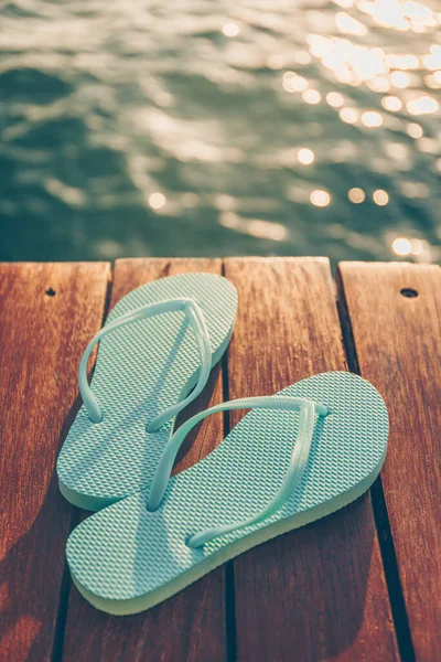 Chanclas en el muelle de madera al atardecer. Resort de vacaciones de lujo. Concepto de escapada de vacaciones — Foto de Stock