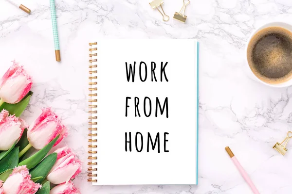 Pink tulips with festive stationary and coffee on white marble background with Work from home wording. Feminine job, gender equality, home office and career concept. Copy space