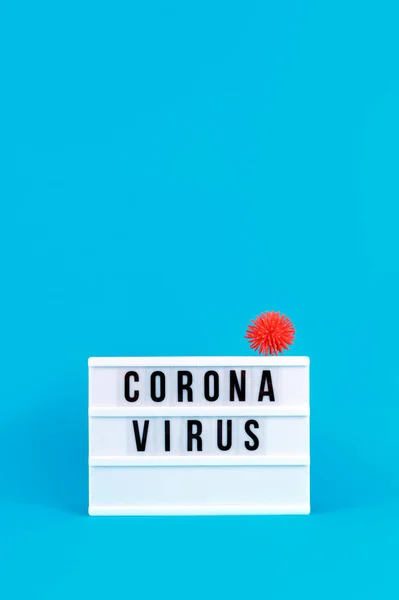 Лайтбокс з коронавірусним написанням та пластиковими кульками, які називаються вірусами на синьому фоні. Епідемія, соціальна ізоляція, концепція коронавірусу COVID-19 — стокове фото