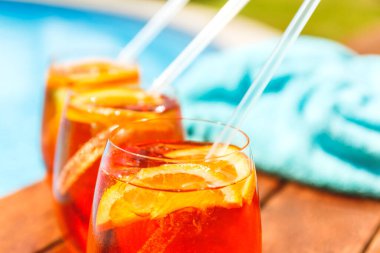 Üç bardak aperol spreyi ve havuz kenarında negroni soğuk kokteyli.