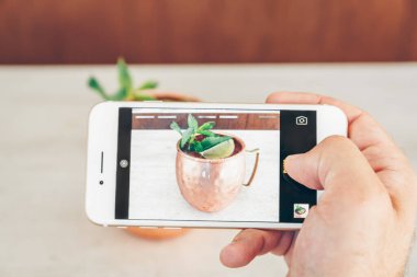 Adam, Moskova katır kokteylinin metal bardakta fotoğrafını çekiyor..