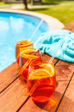 Üç bardak aperol spreyi ve havuz kenarında negroni soğuk kokteyli.