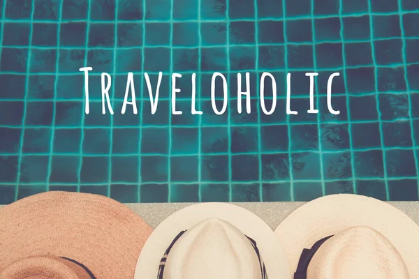Chapéus de palha na borda da piscina com reflexos de palma na água com formulação Traveloholic — Fotografia de Stock
