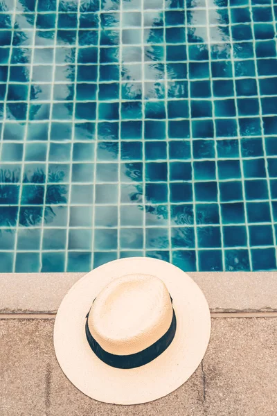 Sombrero de paja en el borde de la piscina con reflejos de palma en el agua — Foto de Stock