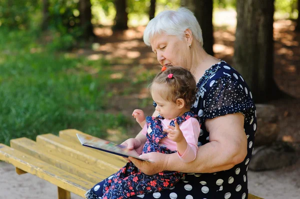 Бабушка и внучка читают книгу в парке — стоковое фото