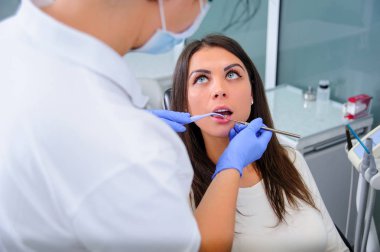 Kadın dişçi hastalarının dişlerinde çalışıyor.