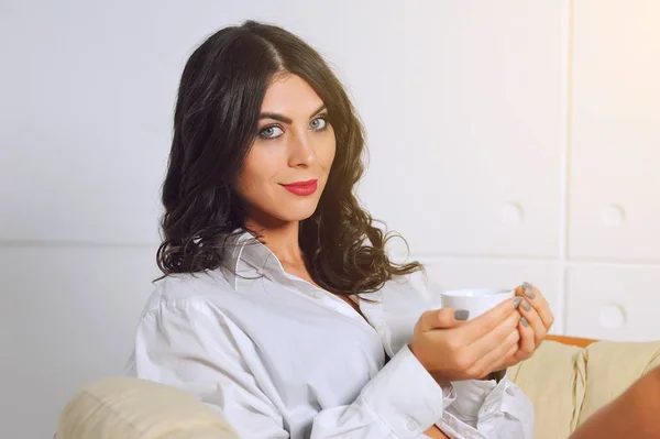 Mädchen im Sessel mit einer Tasse Kaffee am Morgen — Stockfoto