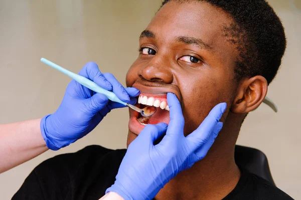 Africano paciente do sexo masculino recebendo tratamento dentário na clínica dentária — Fotografia de Stock