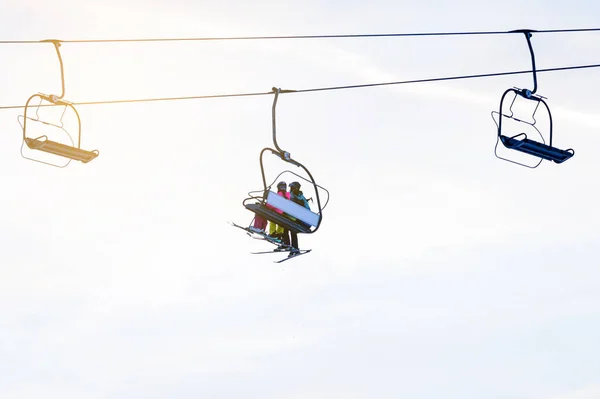 Silhouettes of skiers on chair lifts in the evening — 스톡 사진