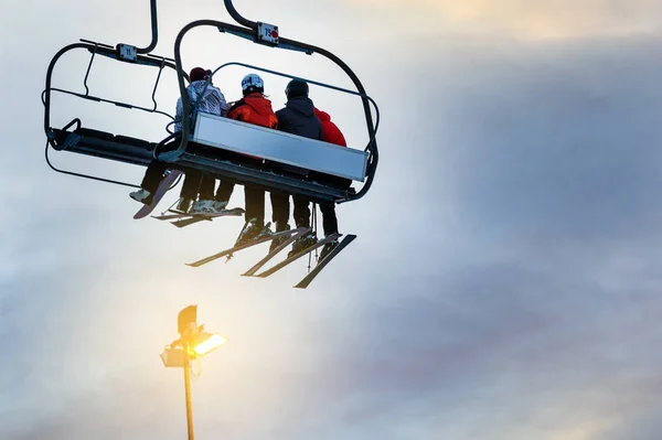 Silhouettes of skiers on chair lifts in the evening — Stock Photo, Image
