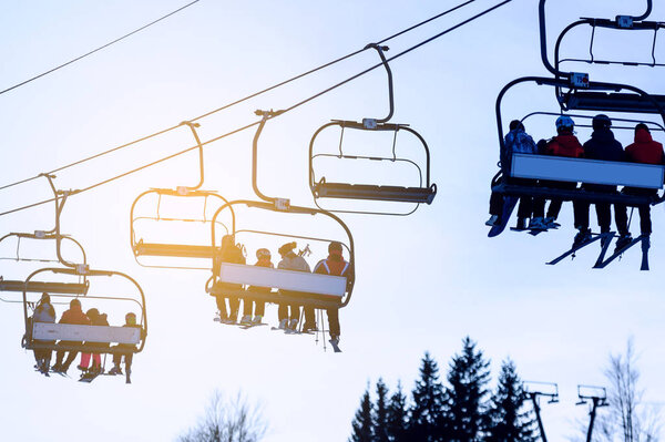 Silhouettes of skiers on chair lifts in the evening