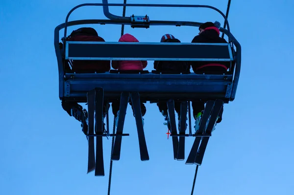 Silhouettes of skiers on chair lifts in the evening — Stock Photo, Image
