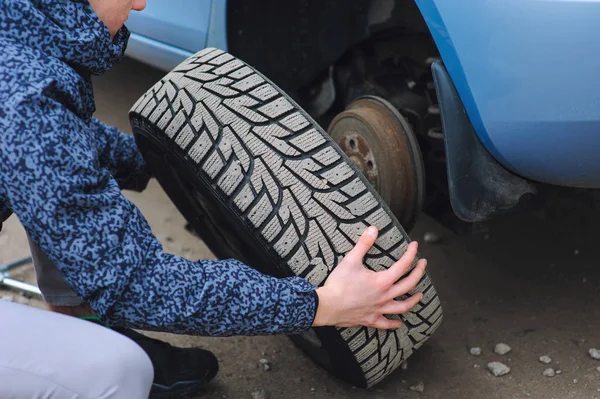 Homem está mudando pneu com roda no carro — Fotografia de Stock