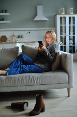 Akşamları evde kanepede uzanan kadınlar akıllı telefon kullanır.